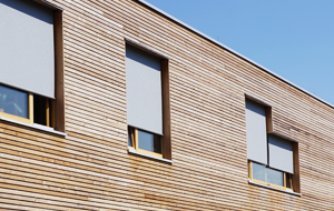 Moderne Holzfassade mit Fenstern und Rollos