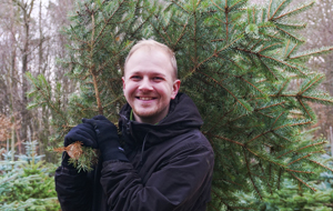 Junger Mann mit selbst geerntetem Weihnachtsbaum
