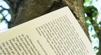 Gedruckter Text auf einer Buchseite vor einem Baum