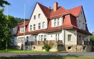 Villenartiges Forstamtsgebäude mit heller Fassade und rotem Spitzdach.