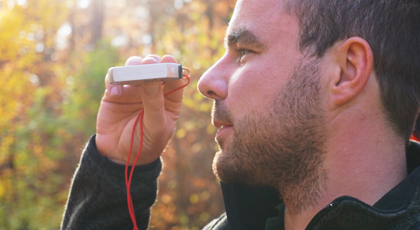 Junger Mann schaut durch einen optischen Sucher in die Baumkronen des Herbstwaldes