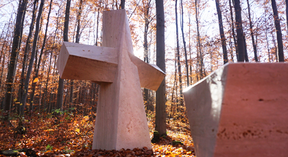 Blick auf ein großes, massives Marmorkreuz im Herbstwald