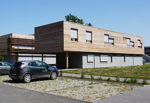 Modernes Gebäude im Bauhaus-Stil mit Holzfassade und davor parkenden Autos