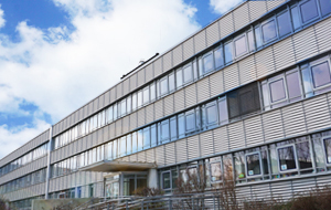 Moderner Flachbau mit Fensterfront, in der sich die Wolken spielgeln