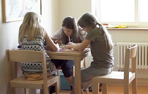 Drei Mädchen sitzen an einem kleinen Tisch und zeichnen. Sie sind sehr konzentriert.
