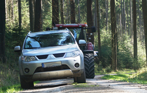 Forstfahrzeug kommt nicht an einem auf dem Waldweg geparkten PKW vorbei