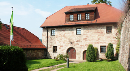 Historisches Gebäude mit rotem Ziegeldach. An der Fassade ist ein Hirschgeweih